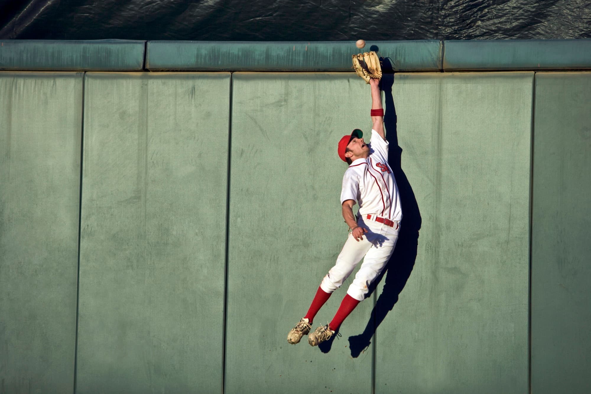 An outfielder leaping at the wall to catch a fly ball