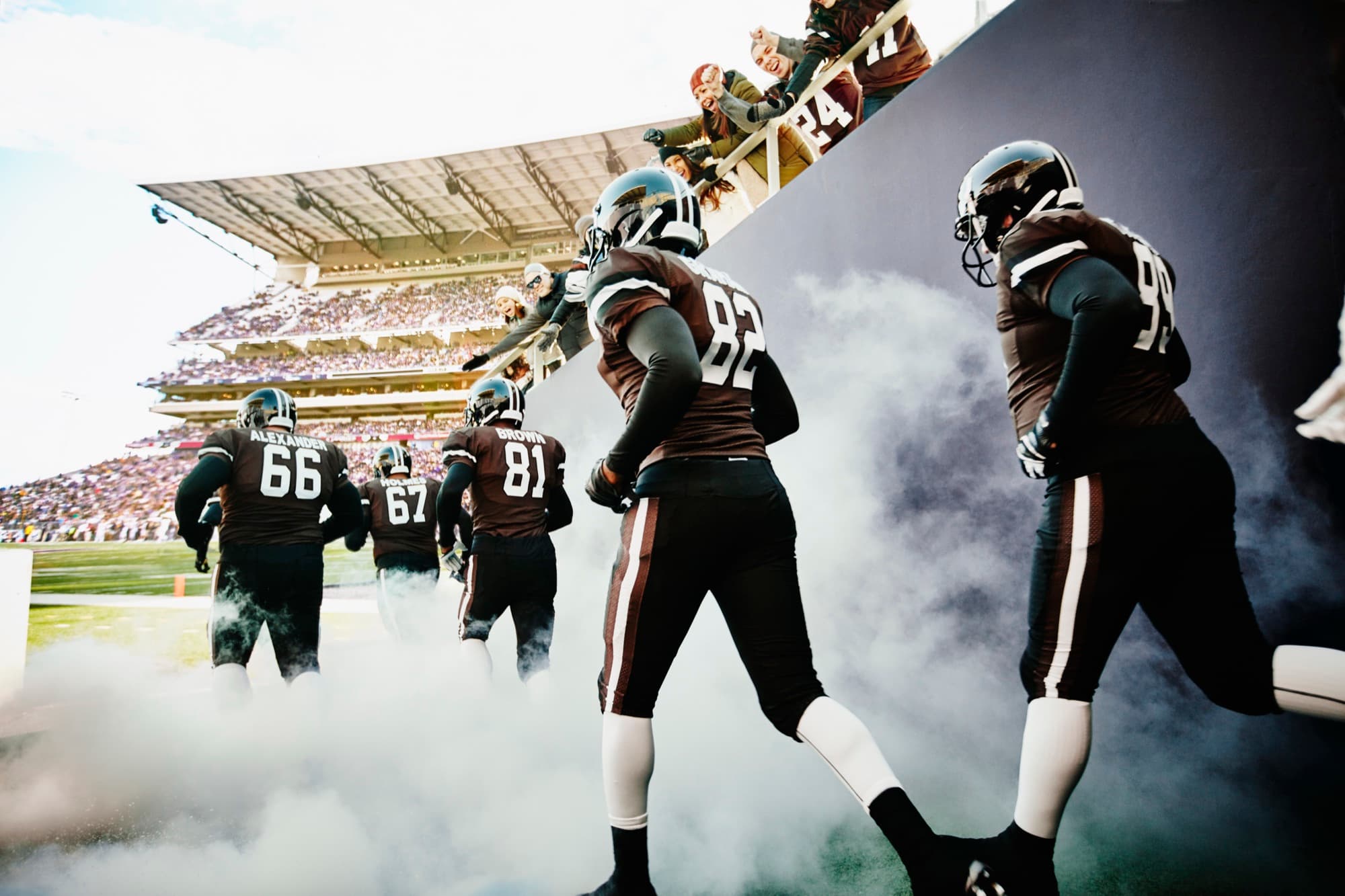 A football team running out of the tunnel as fans cheer from above