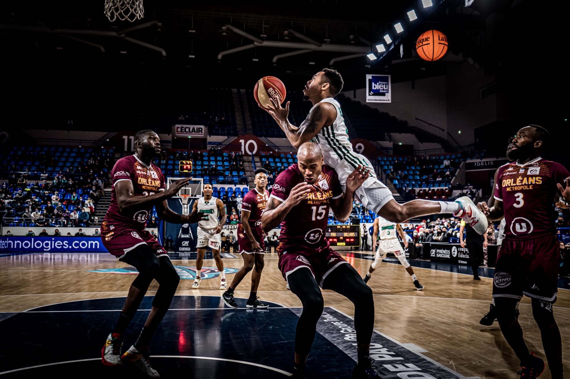 An Élan Béarnais player rising for a layup over Orléans defenders